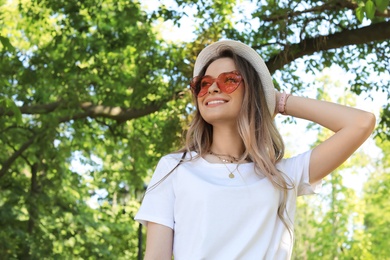 Photo of Portrait of happy woman with heart shaped glasses in summer park. Space for text