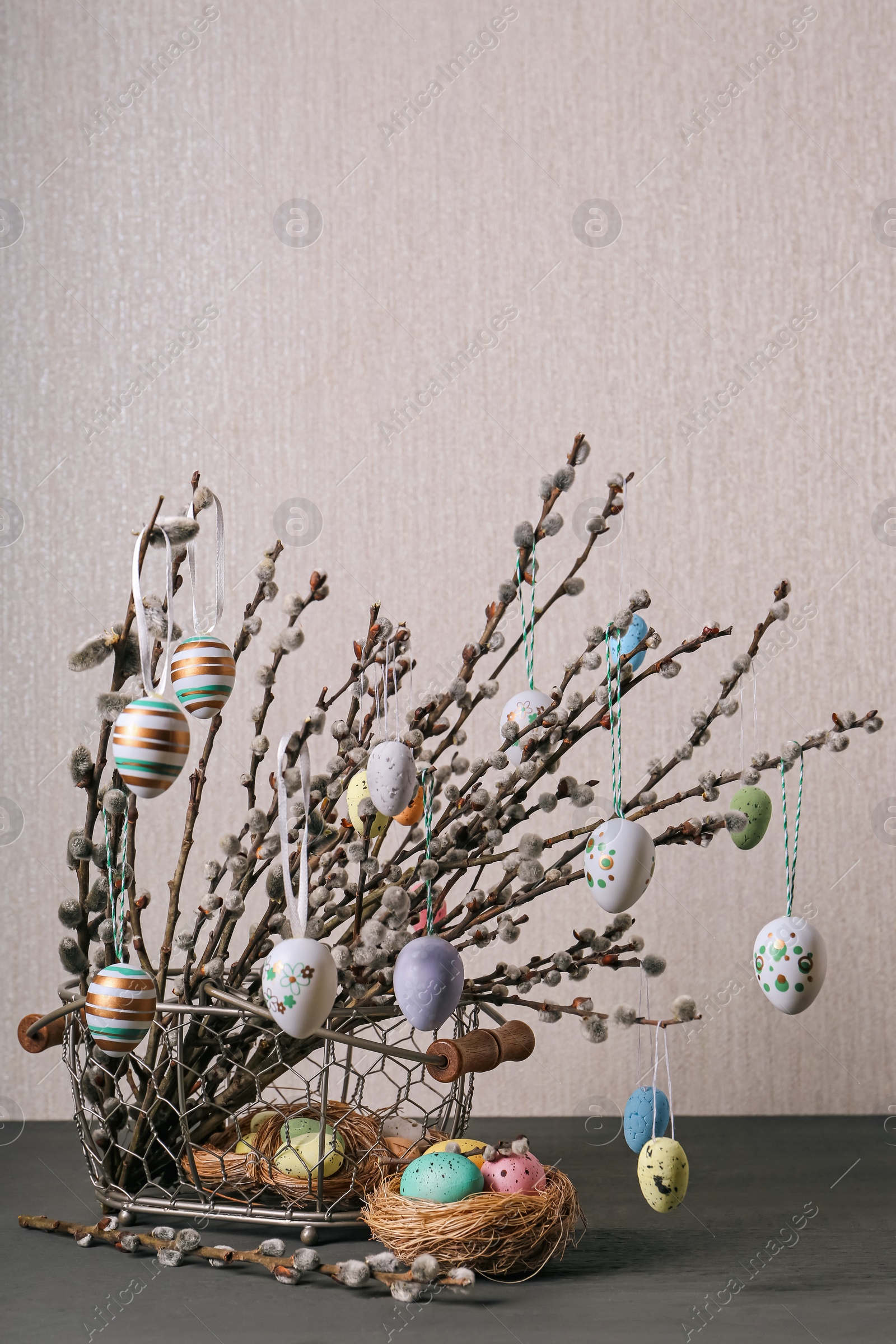 Photo of Beautiful willow branches with painted eggs and Easter decor on light grey wooden table