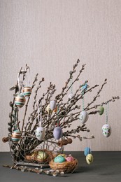Photo of Beautiful willow branches with painted eggs and Easter decor on light grey wooden table