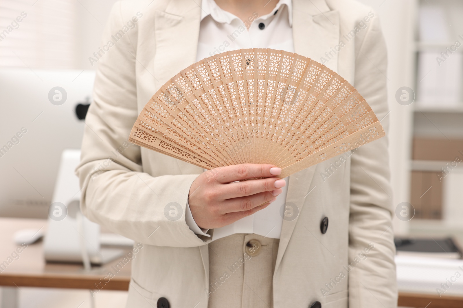 Photo of Businesswoman with hand fan in office, closeup