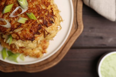 Tasty parsnip cutlets with green onion on wooden table, top view