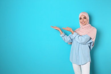 Photo of Portrait of young Muslim woman in hijab against color background. Space for text