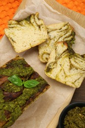 Freshly baked pesto bread with basil on table, flat lay