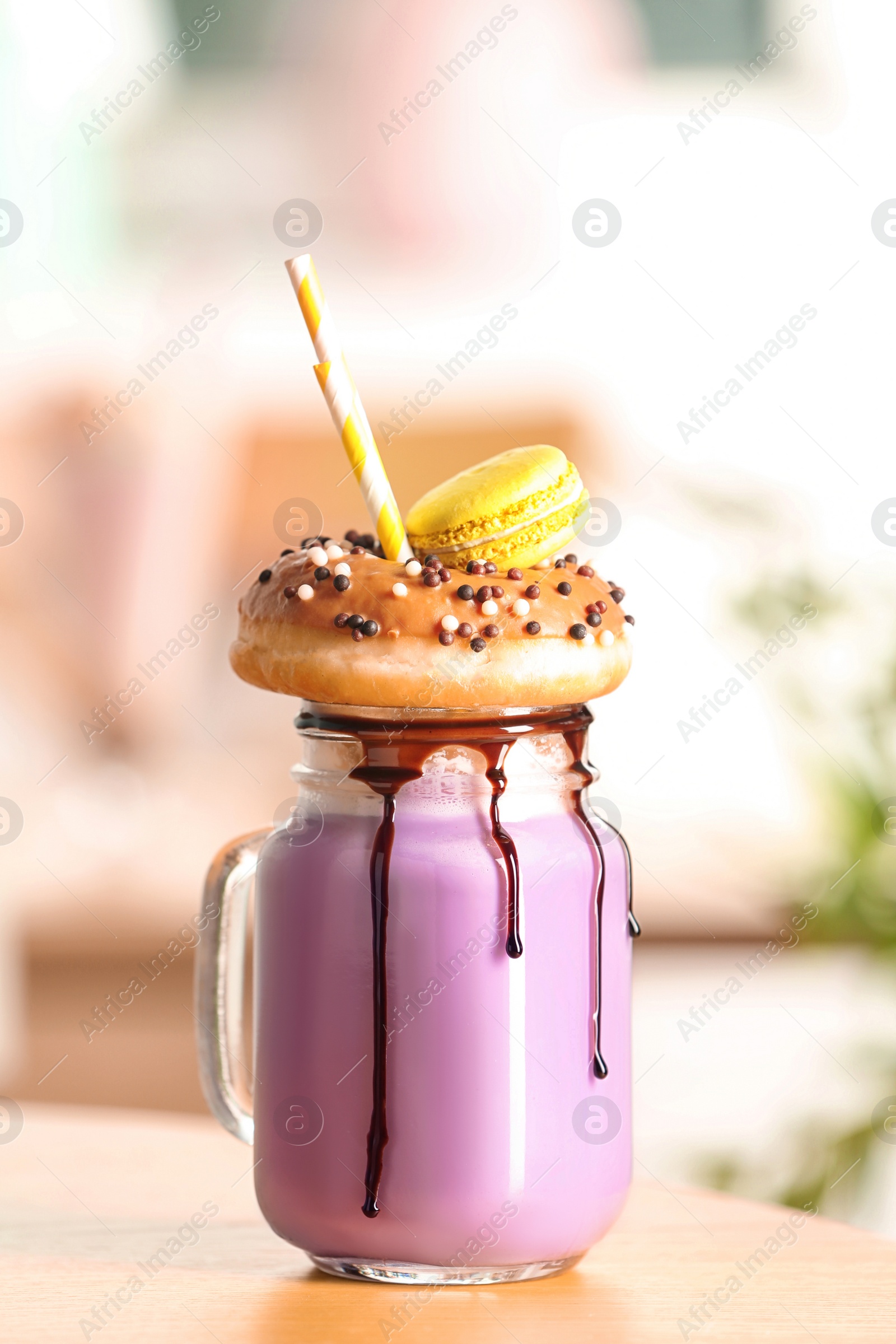 Photo of Mason jar with delicious milk shake on table against blurred background