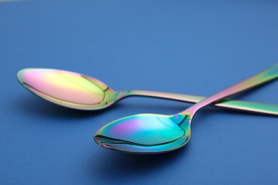 Photo of New clean colorful tablespoons on blue background