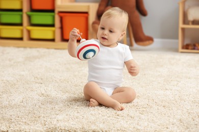 Photo of Children toys. Cute little boy playing with spinning top on rug at home