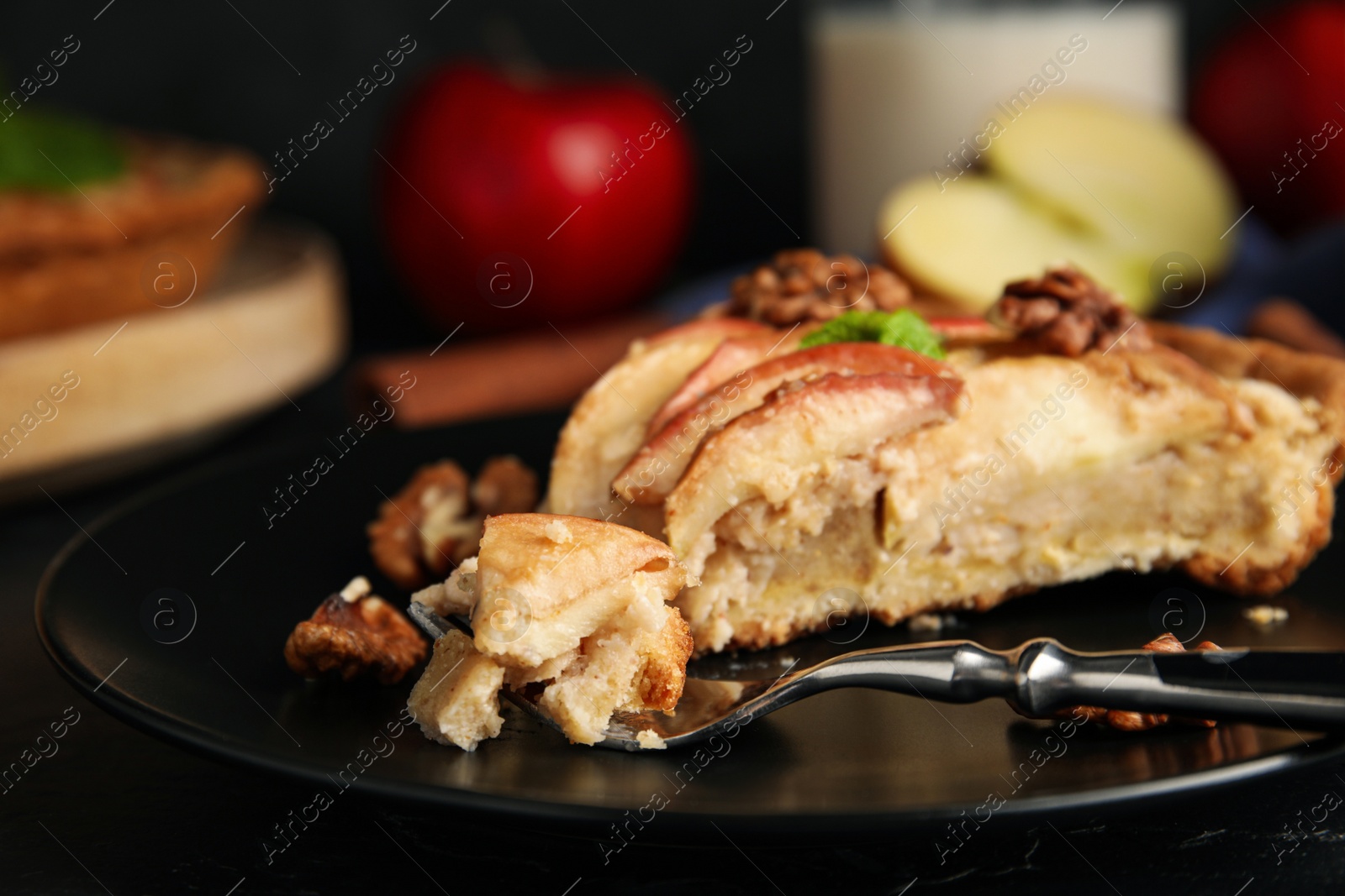Photo of Fork with delicious apple pie on black table, closeup