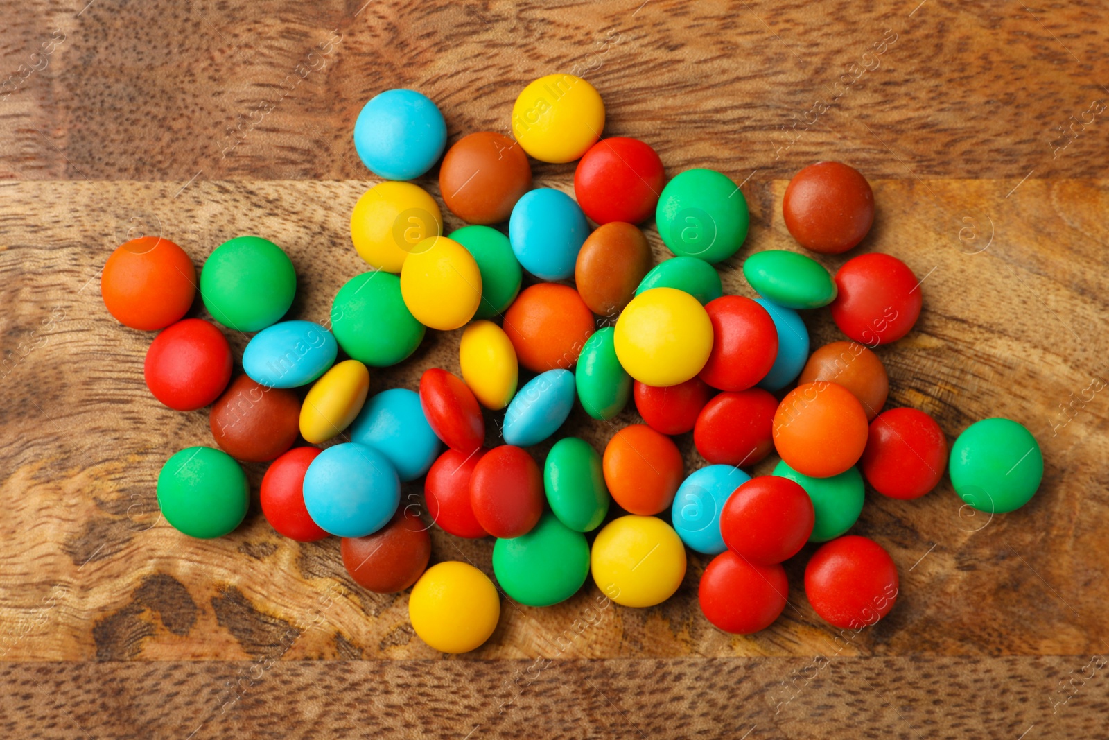 Photo of Tasty colorful candies on wooden table, flat lay