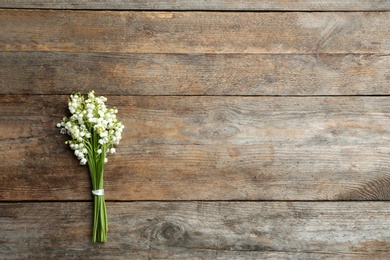 Beautiful lily of the valley bouquet on wooden background, top view. Space for text