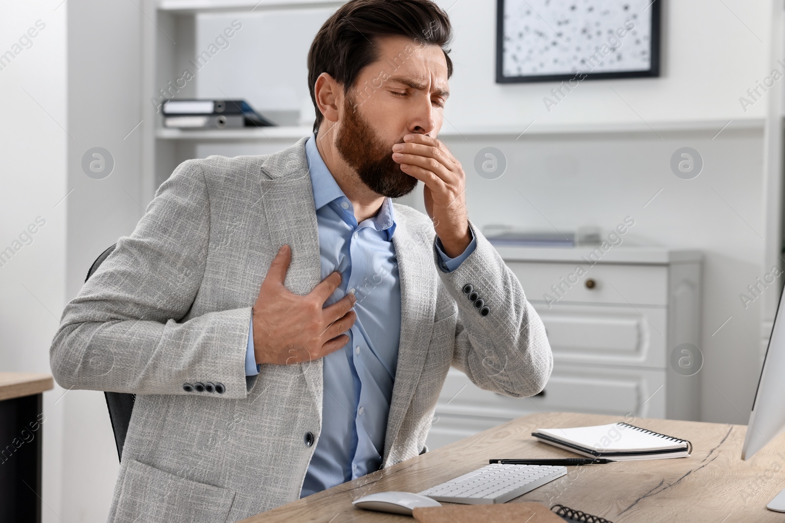 Photo of Sick man coughing at workplace in office. Cold symptoms