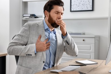 Sick man coughing at workplace in office. Cold symptoms