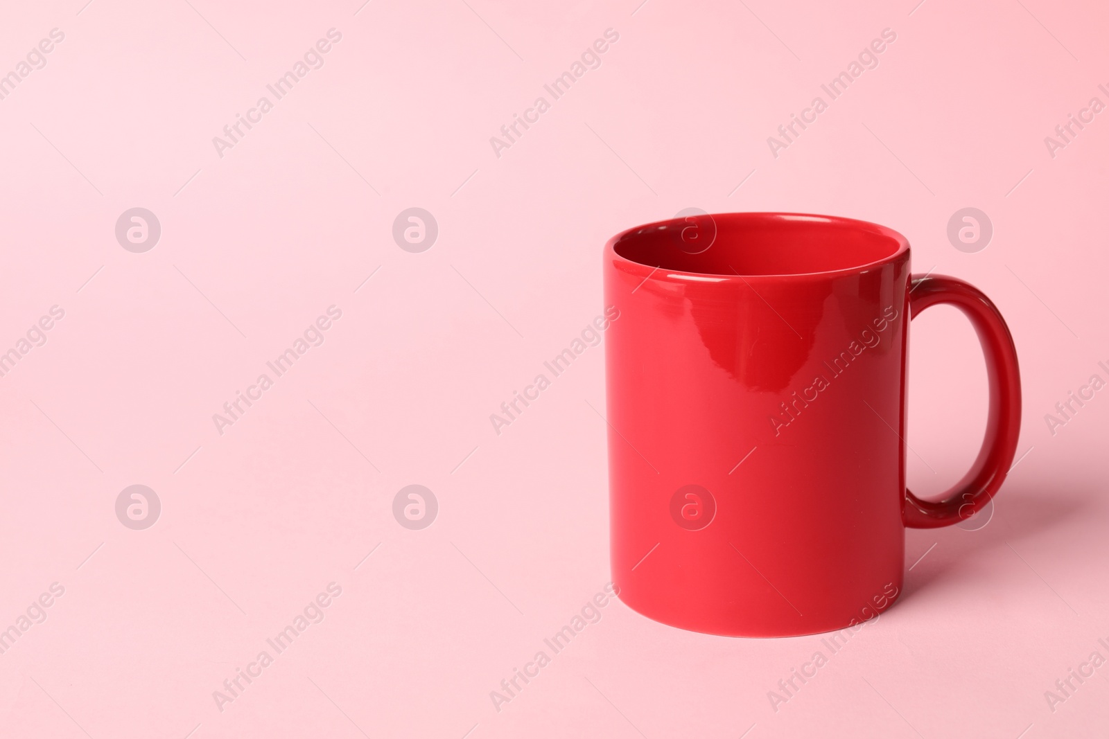 Photo of One red ceramic mug on pink background, space for text