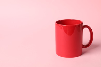 One red ceramic mug on pink background, space for text