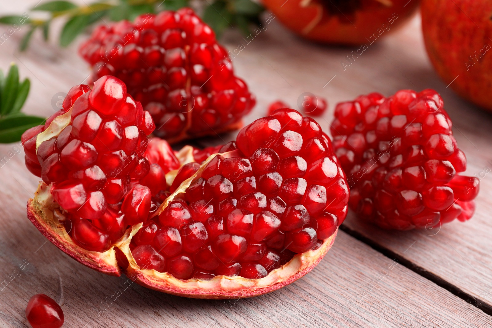 Photo of Cut fresh pomegranate on wooden table, closeup