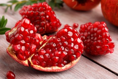 Photo of Cut fresh pomegranate on wooden table, closeup