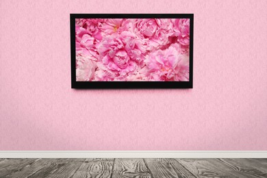 Image of TV screen with beautiful peony flowers on pink wall in room