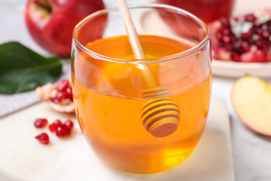 Photo of Honey, apples and pomegranate seeds on white marble table, closeup. Rosh Hashanah holiday