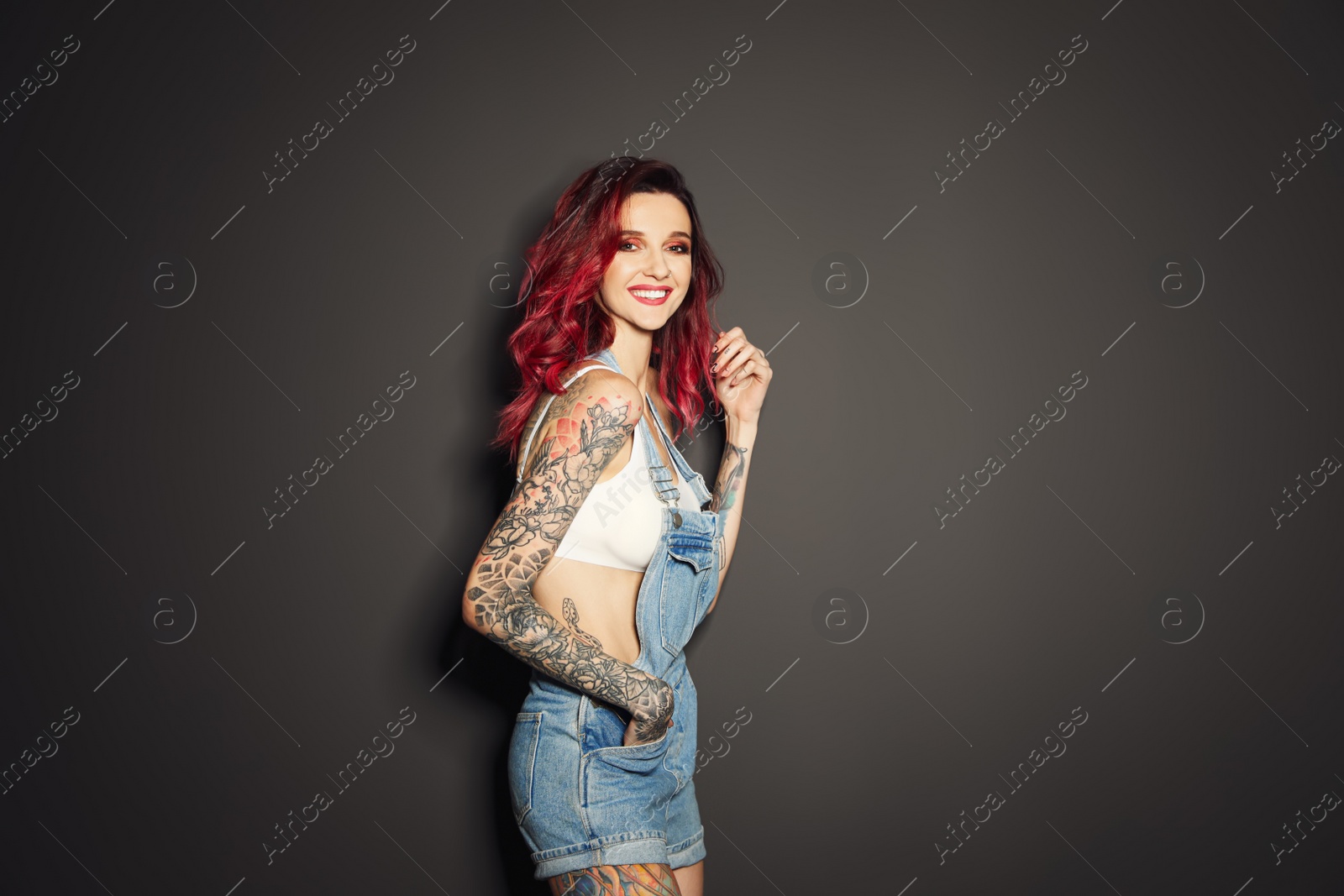 Photo of Beautiful woman with tattoos on body against black background