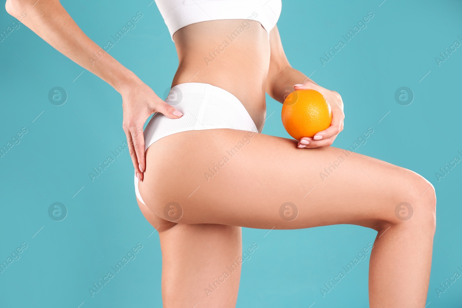 Photo of Closeup view of slim woman in underwear with orange on color background. Cellulite problem concept