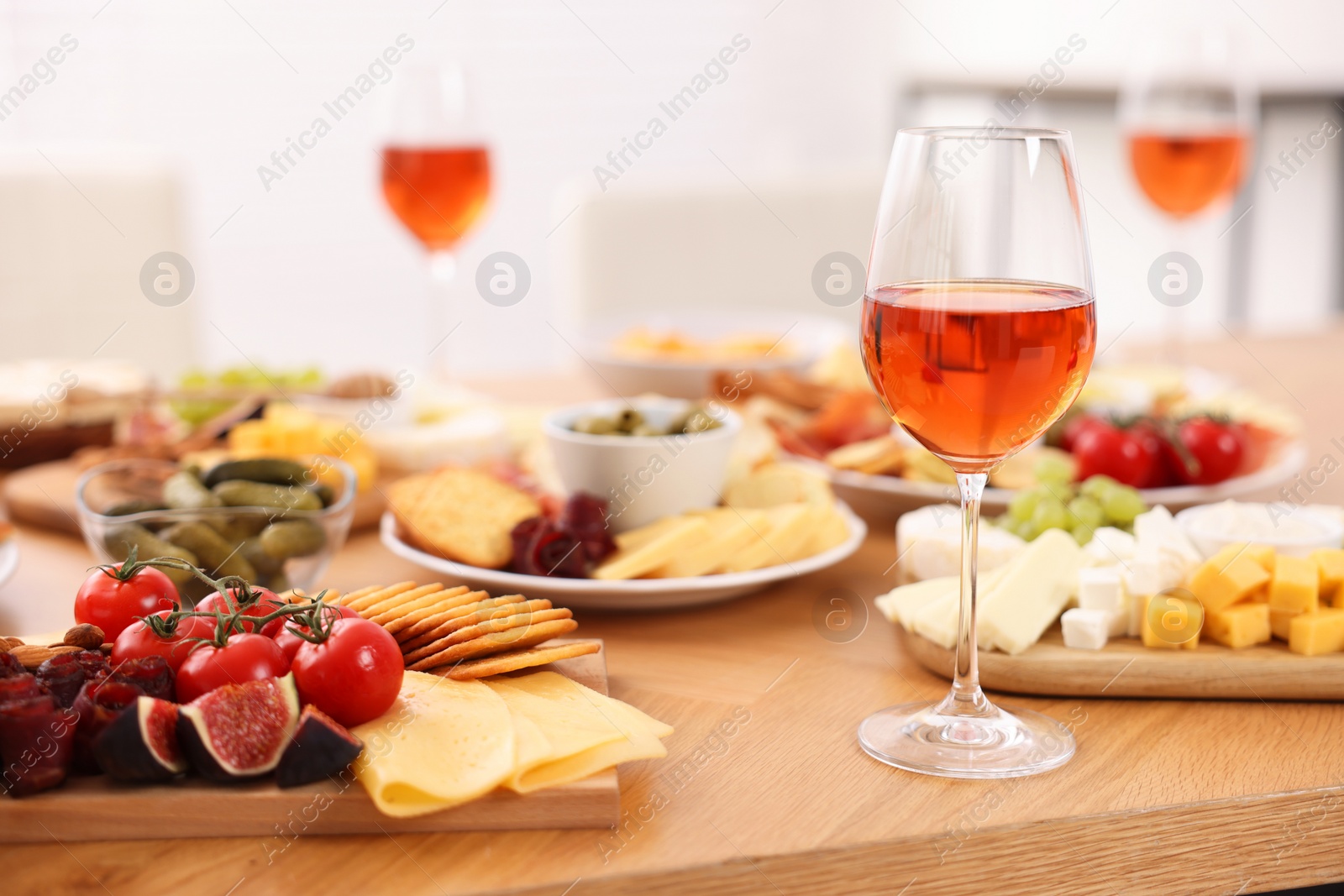 Photo of Rose wine and assorted appetizers served on wooden table indoors
