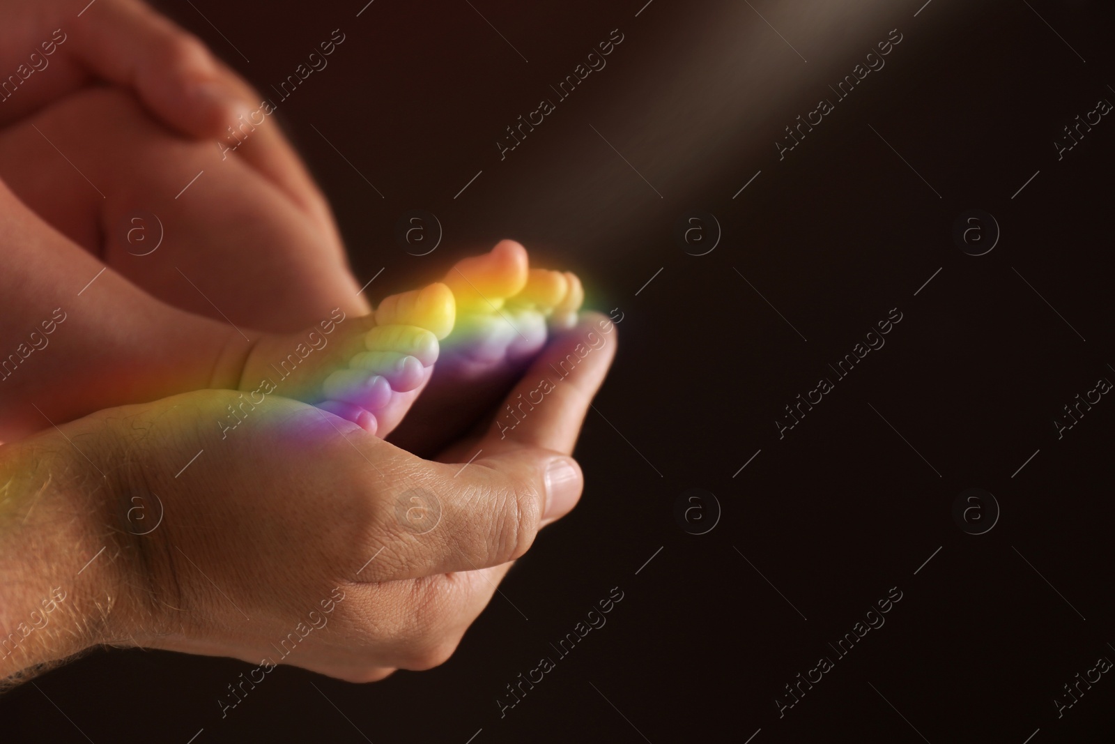 Image of National rainbow baby day. Father holding his little child against dark background, closeup. Space for text