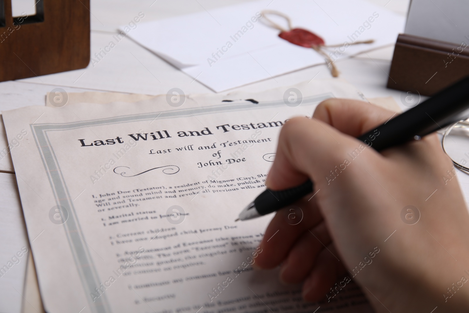 Photo of Woman signing last will and testament at table, closeup