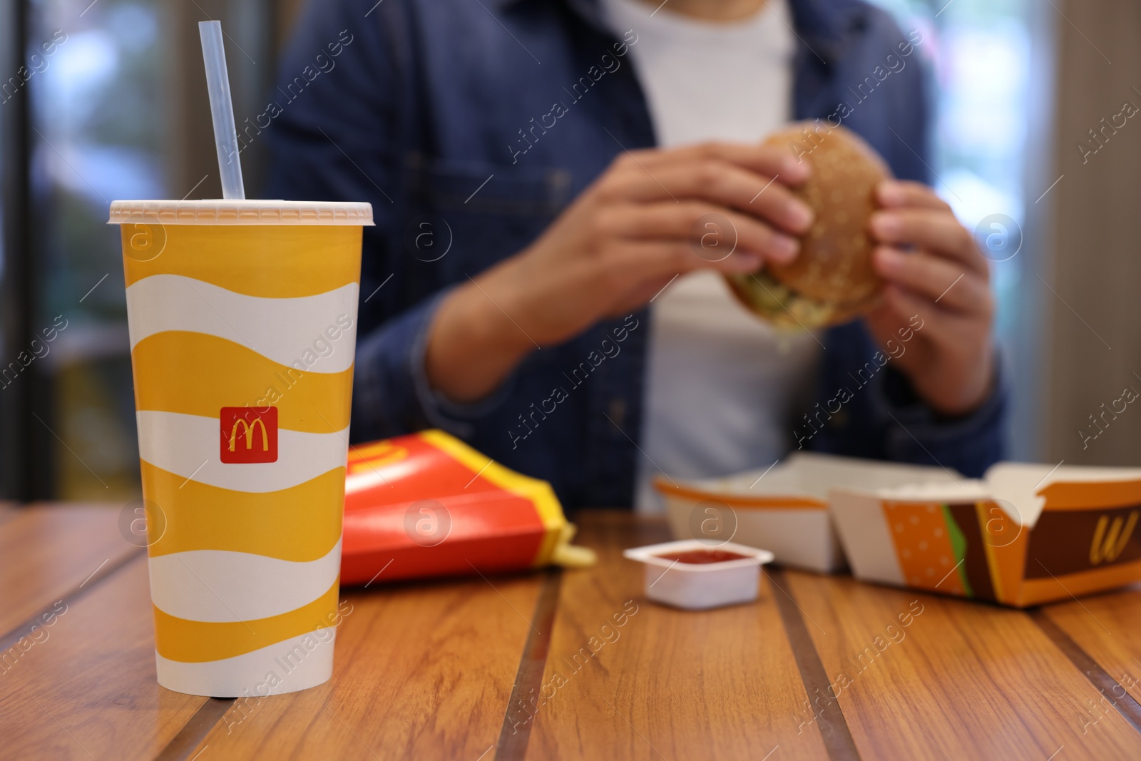 Photo of Lviv, Ukraine - October 9, 2023: Woman with McDonald's menu at wooden table in restaurant, selective focus