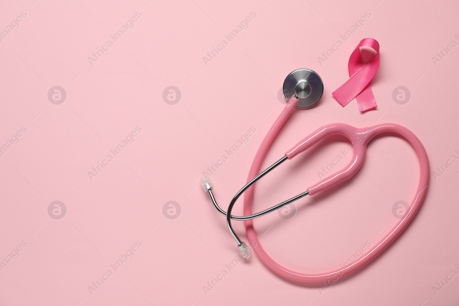 Photo of Breast cancer awareness. Pink ribbon and stethoscope on color background, flat lay. Space for text