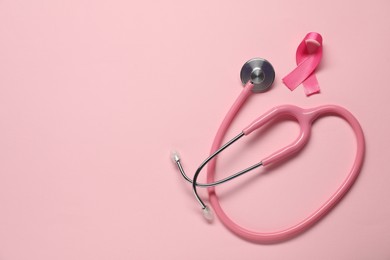 Breast cancer awareness. Pink ribbon and stethoscope on color background, flat lay. Space for text