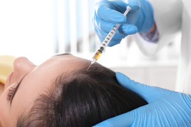 Photo of Young woman with hair loss problem receiving injection in salon, closeup