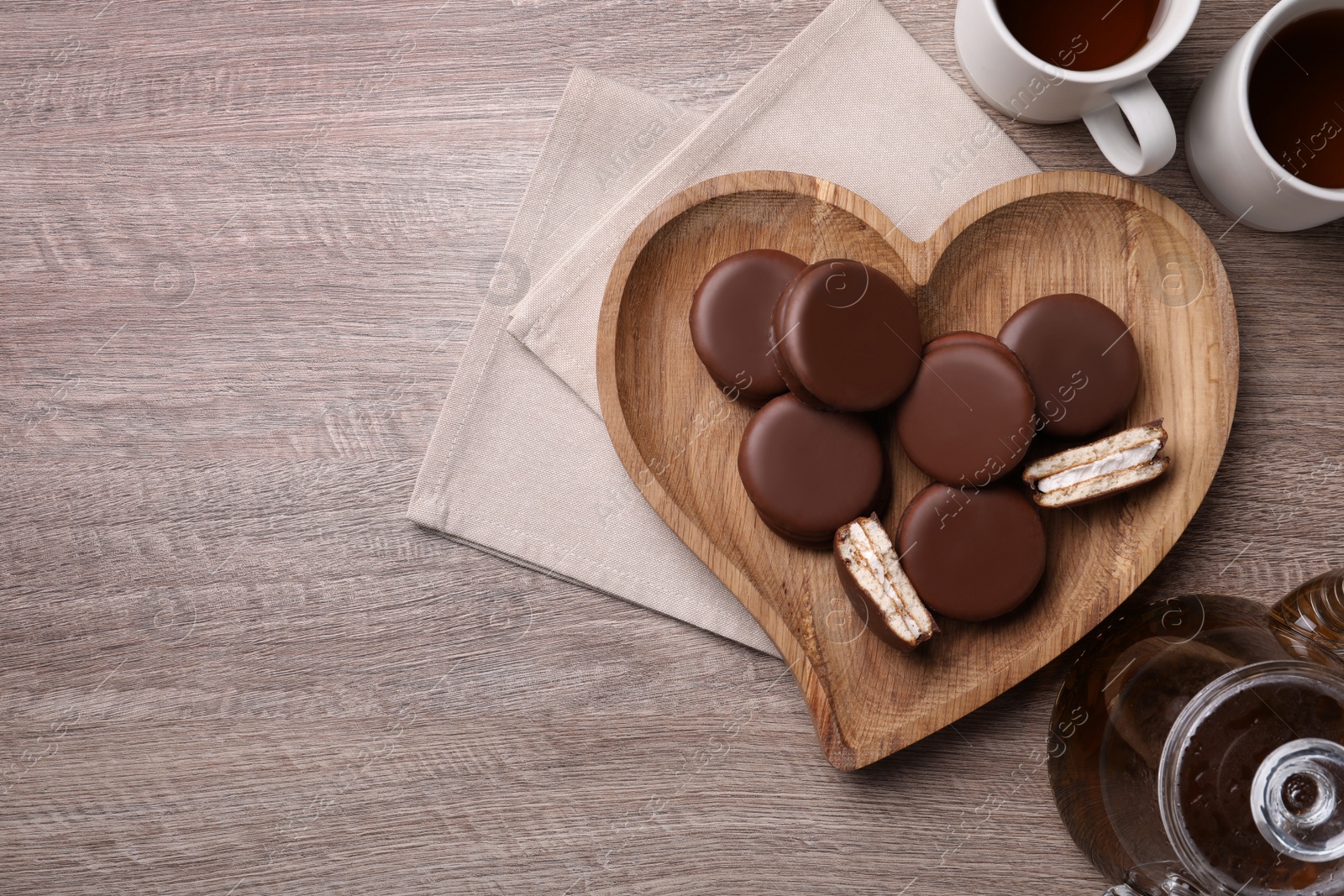 Photo of Tasty choco pies and tea on wooden table, flat lay. Space for text