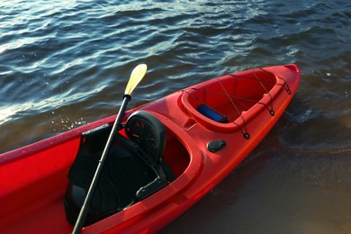 Photo of Beautiful modern red kayak with paddle on beach