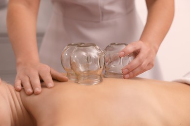 Therapist giving cupping treatment to patient indoors, closeup