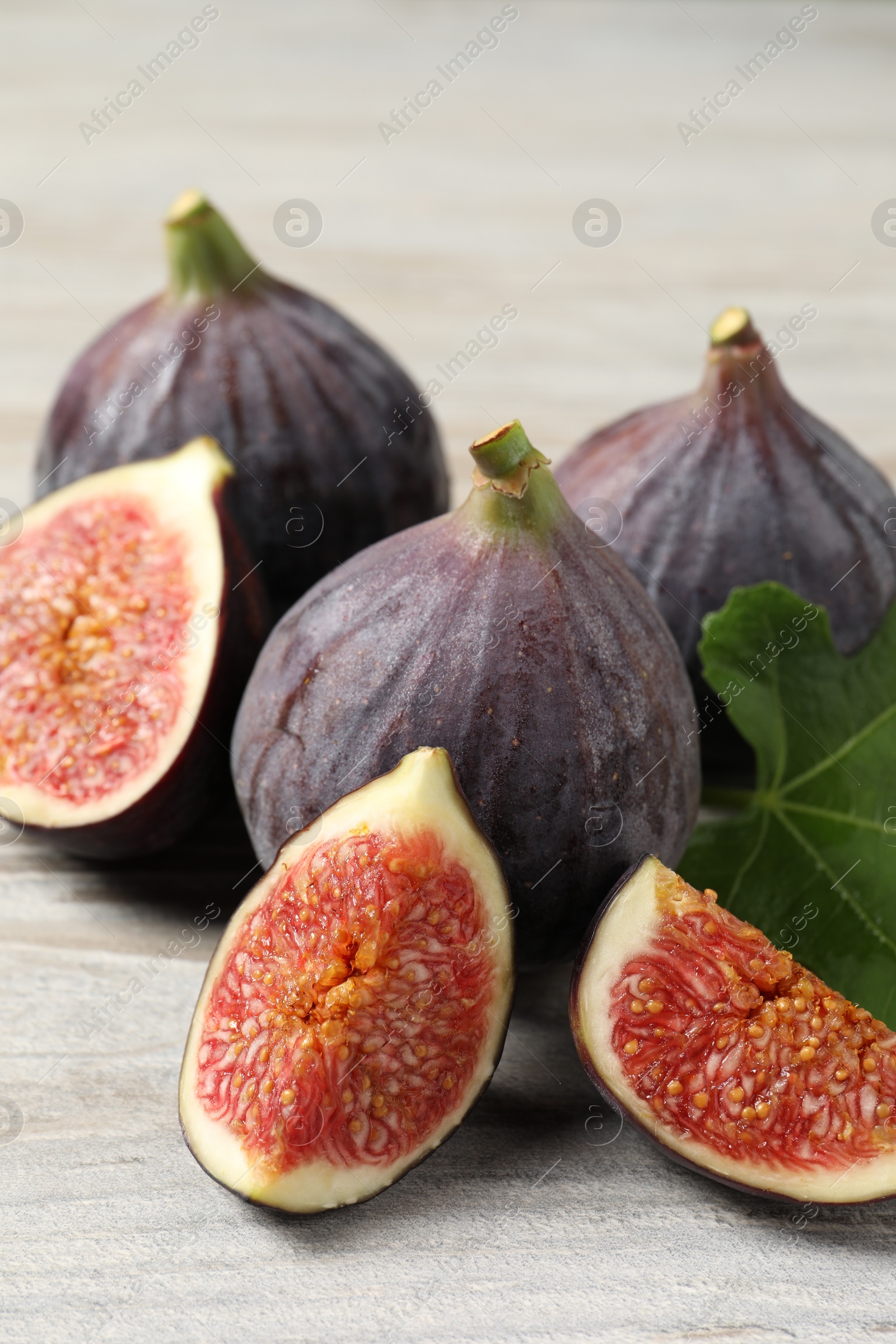 Photo of Whole and cut ripe figs on light wooden table, closeup