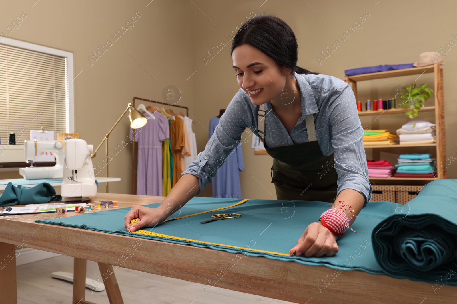 Photo of Dressmaker working with light blue fabric in atelier