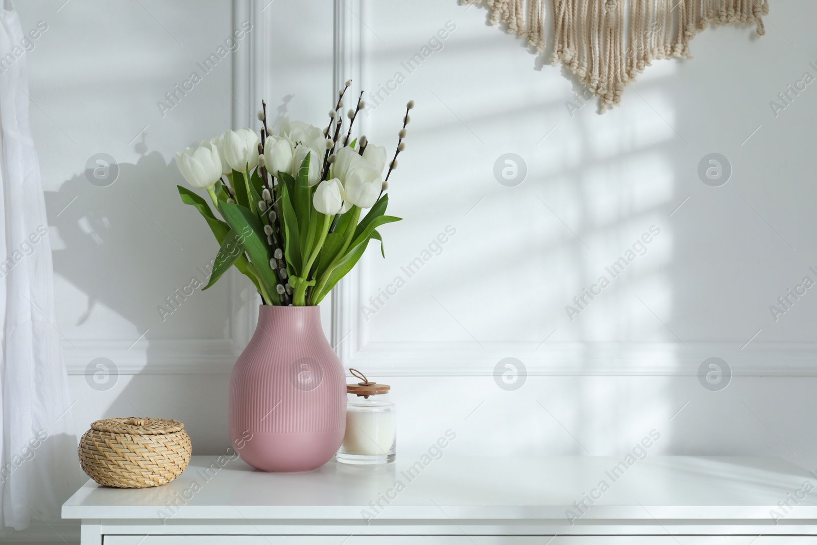 Photo of Beautiful bouquet of willow branches and tulips in vase indoors, space for text