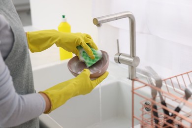 Woman washing plate above sink in modern kitchen, closeup