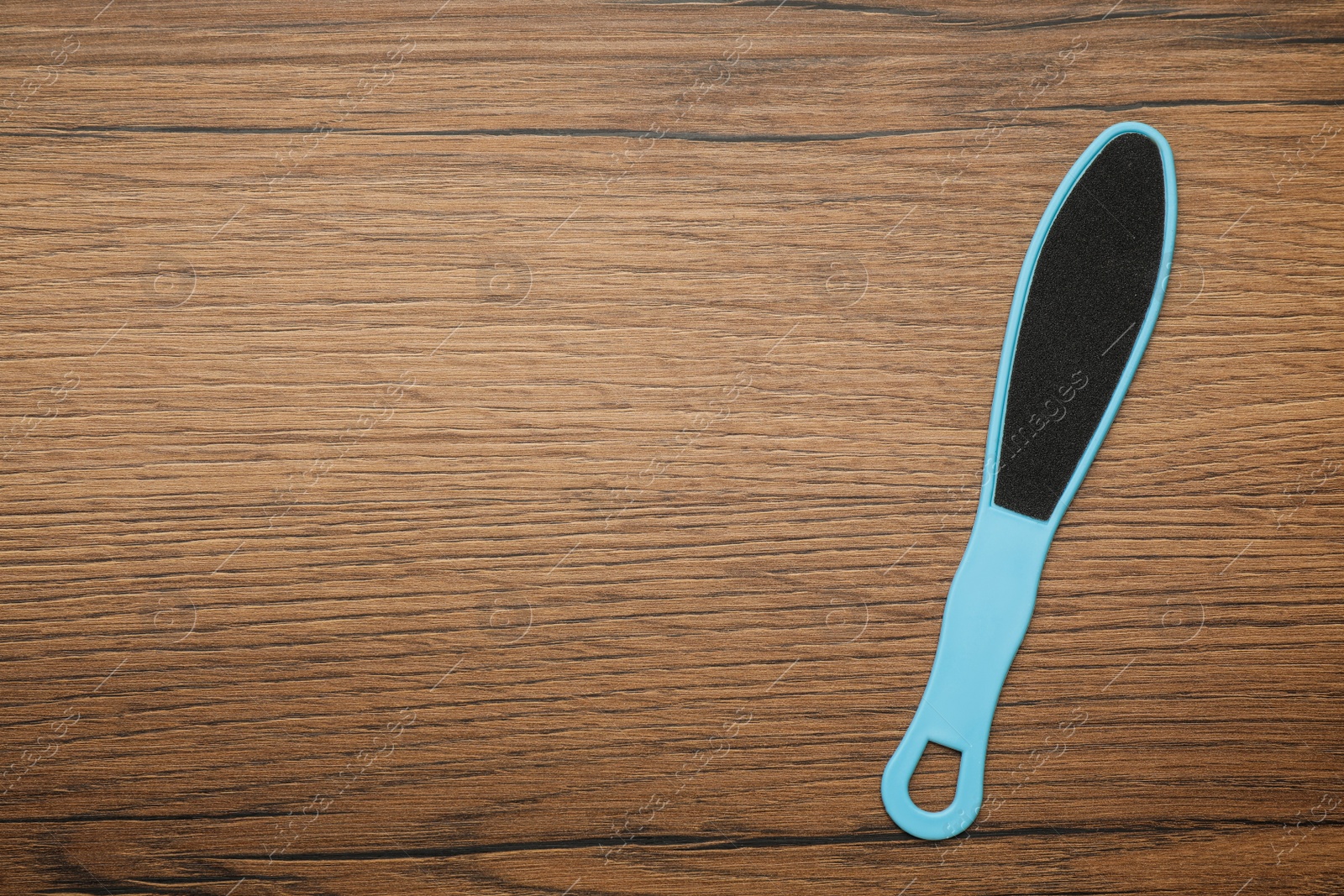 Photo of Blue foot file on wooden table, top view with space for text. Pedicure tool