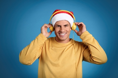 Photo of Happy man with headphones on blue background. Christmas music