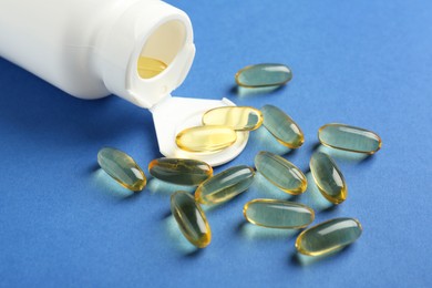 Photo of Bottle of vitamin capsules on blue background, closeup