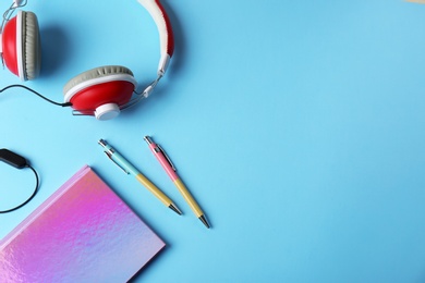 Photo of Sparkly notebook, pens and headphones on color background, flat lay. Space for text