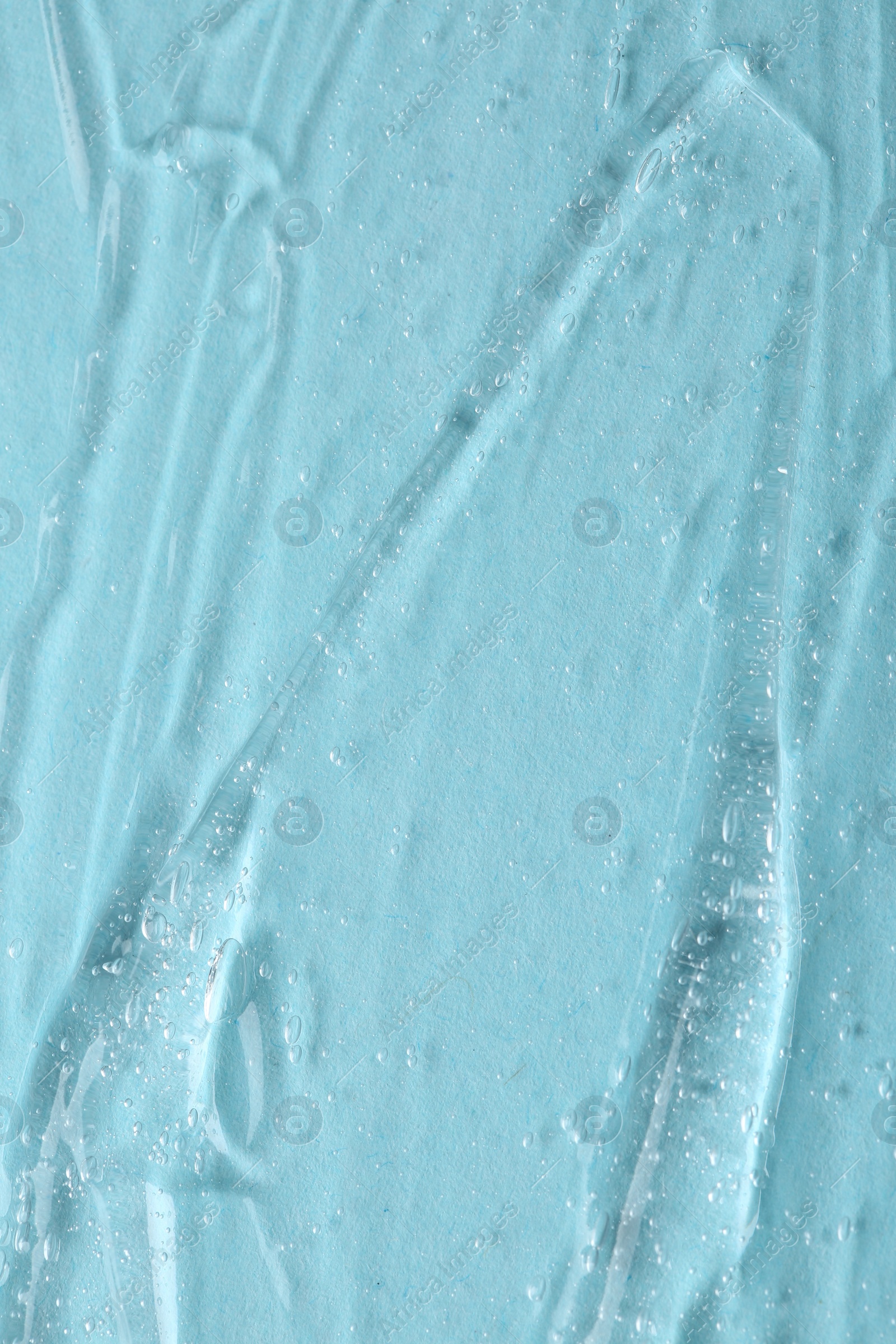 Photo of Clear cosmetic serum on light blue background, macro view