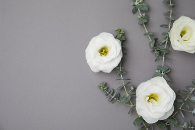 Fresh eucalyptus leaves with flowers and space for design on color background, flat lay