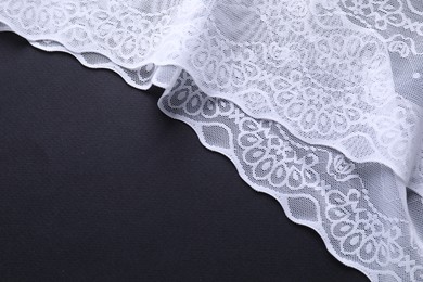 Photo of White lace on black background, top view. Space for text