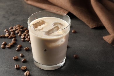Photo of Coffee cream liqueur in glass and beans on grey table, space for text