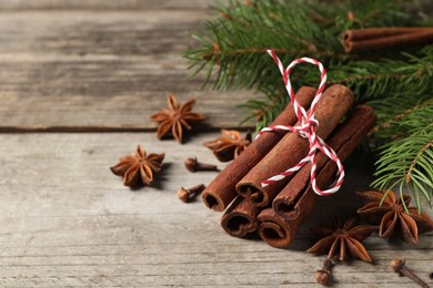 Photo of Different spices and fir branches on wooden table, space for text