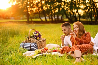 Photo of Happy young couple having picnic in green park