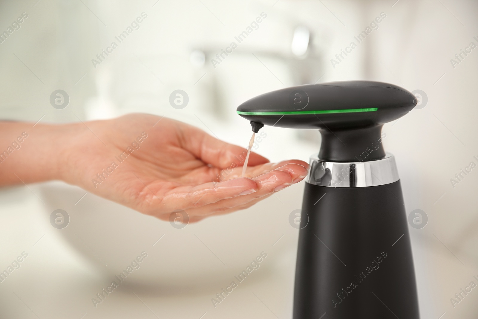 Photo of Woman using automatic soap dispenser in bathroom, closeup