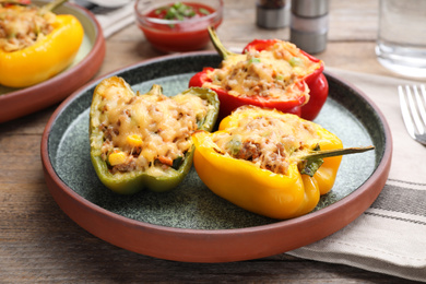 Photo of Tasty stuffed bell peppers served on wooden table, closeup