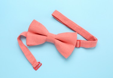 Photo of Stylish pink bow tie on light blue background, top view